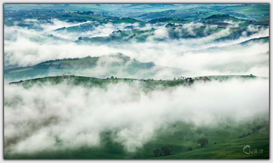 Paesaggio nebbioso in collina, onde bianche di nebbia accarezzano le dolci colline